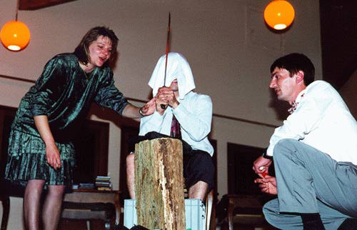 Blindfolded guy about to swing a machete down on a block
of wood